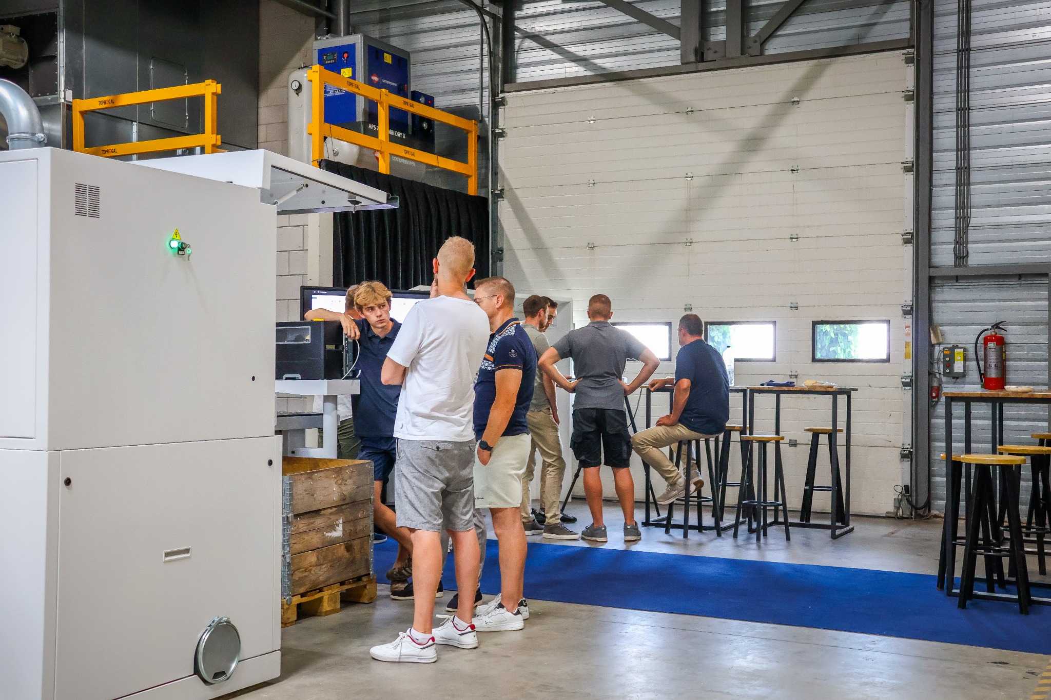 Bezoekers in gesprek tussen de KDT-machines en statafels in de showroom.
